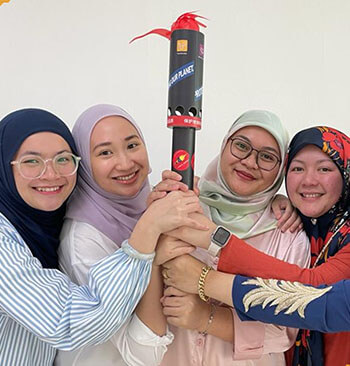 Female employees from Brunei holding a torch